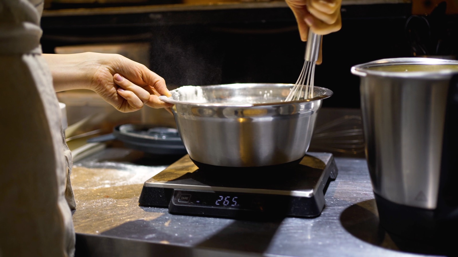 A chef weighing ingredients on a kitchen scale
